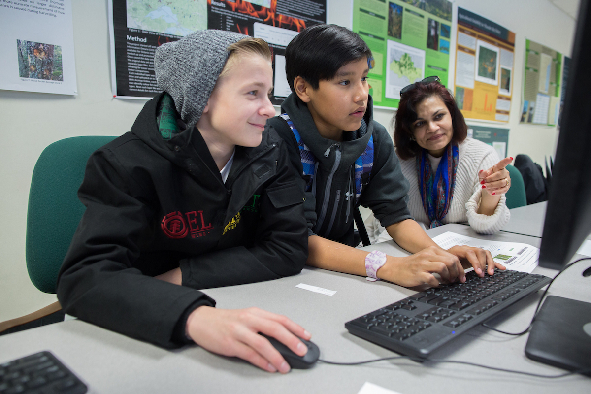 Students and educator completing computational thinking activity at a computer