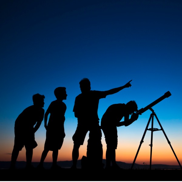 Adult and children looking through telescope