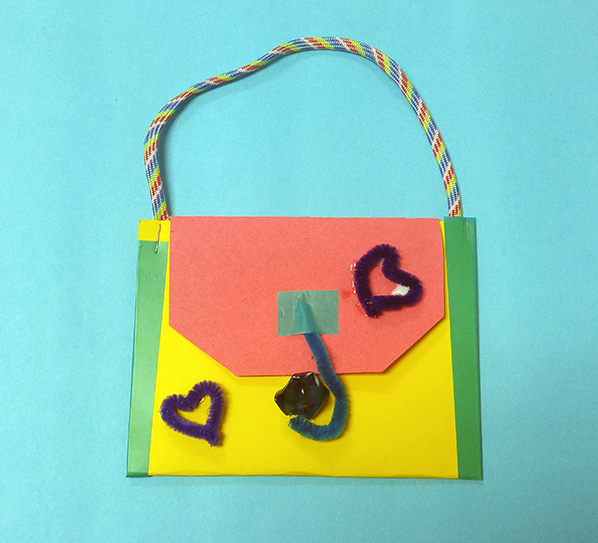 Shown is a colour photograph of a pouch made from paper and yarn.