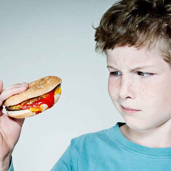 a boy looks at a hamburger