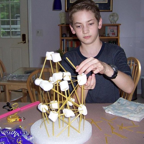 Student making structure with pasta and marshmallows