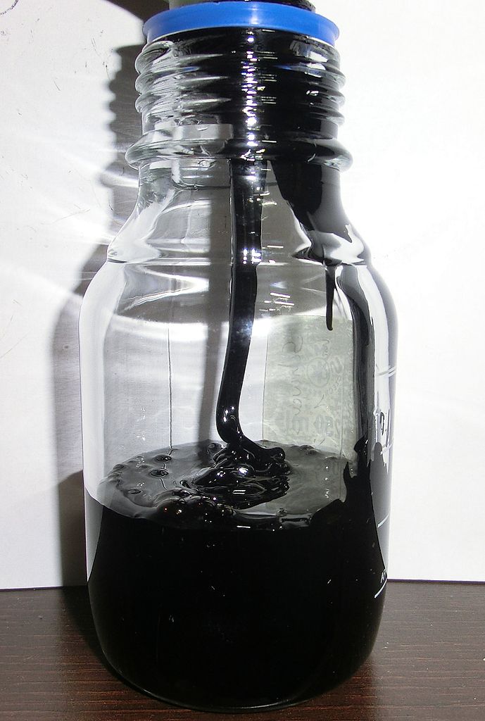 Shown is a colour photograph of bunker fuel being poured into a glass jar.