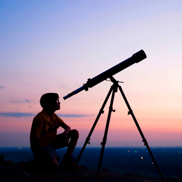 Boy looking through telescope at night