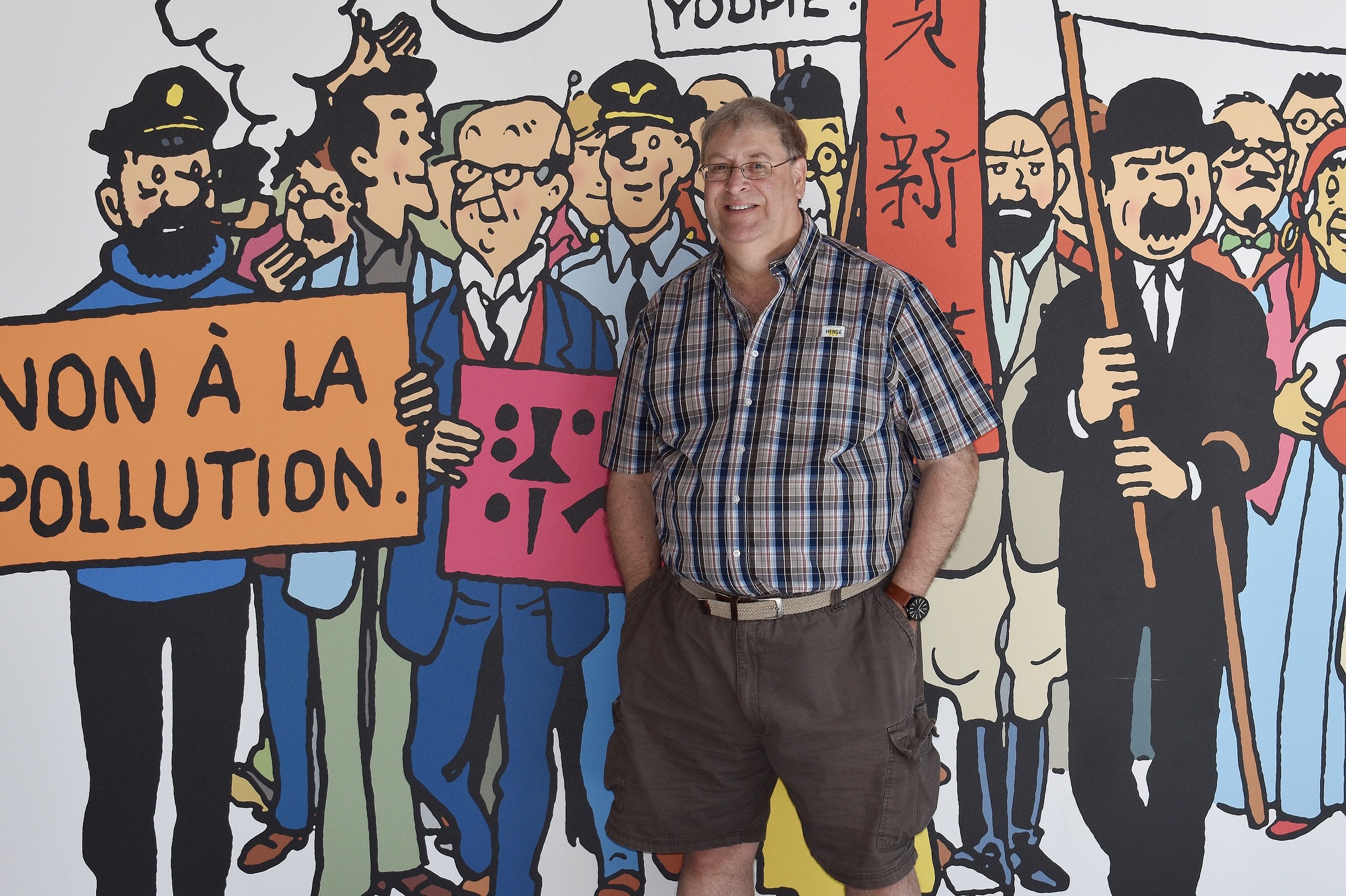 Photo de Luc-Baudouin St-Cyr devant une murale de bande dessinée
