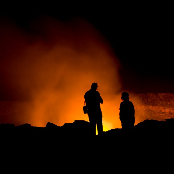 Volcanologists looking at glowing lava