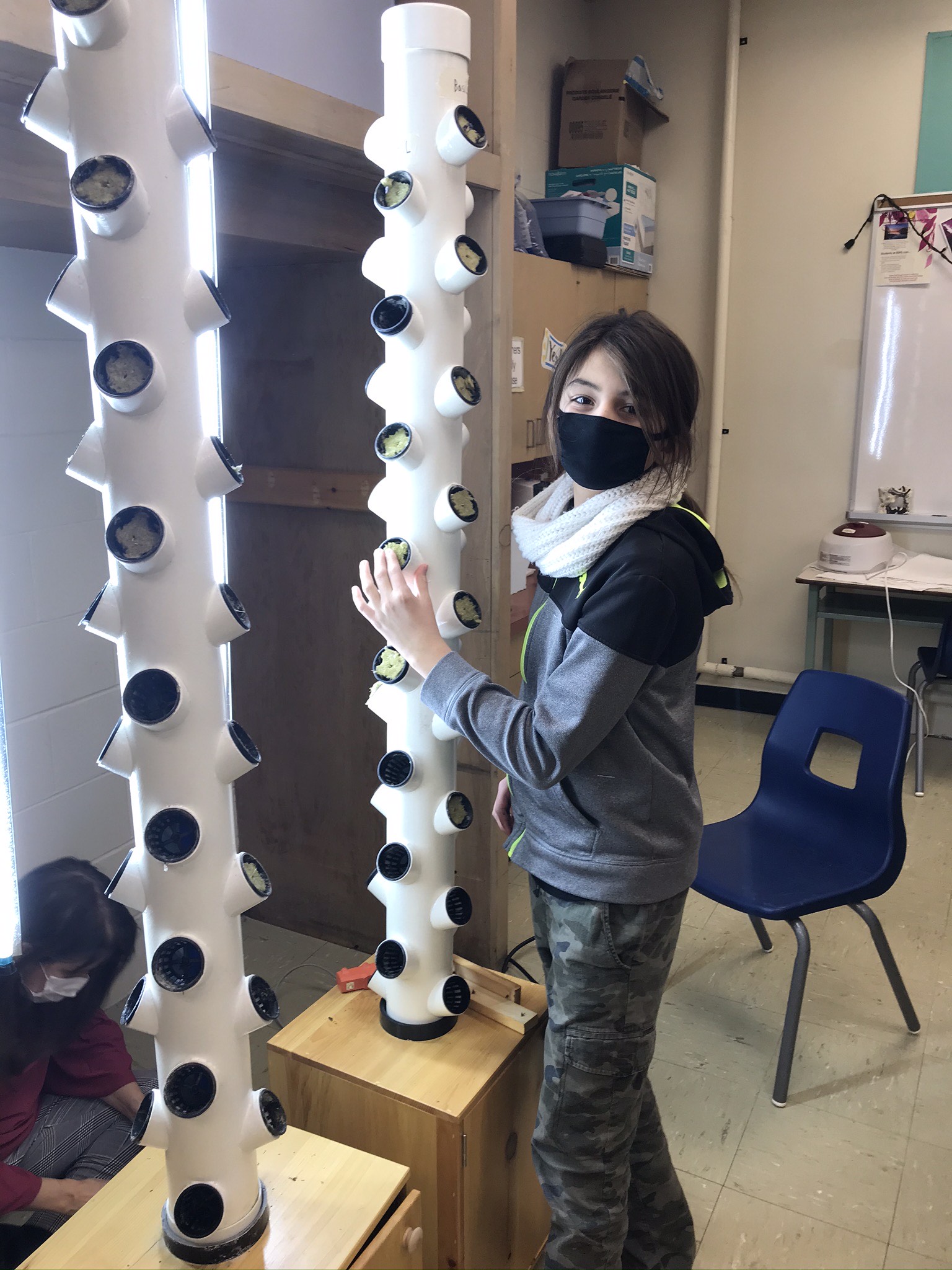 Student stands beside their class project