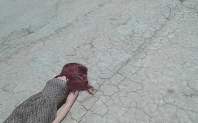 Girl in a dress lying face-down on drought-stricken ground