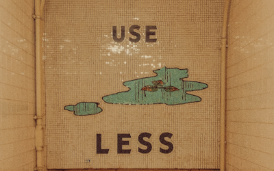 Sign painted in the entrance to a subway reading "Use Less."