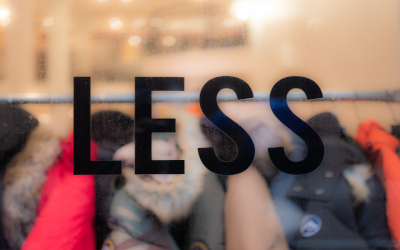 Sign on a store window reading "LESS"