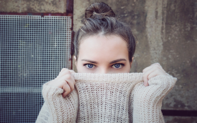 Woman holding a knit sweater over the lower half of her face