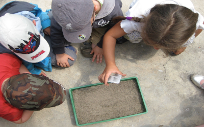 Children kneeling around a planter box