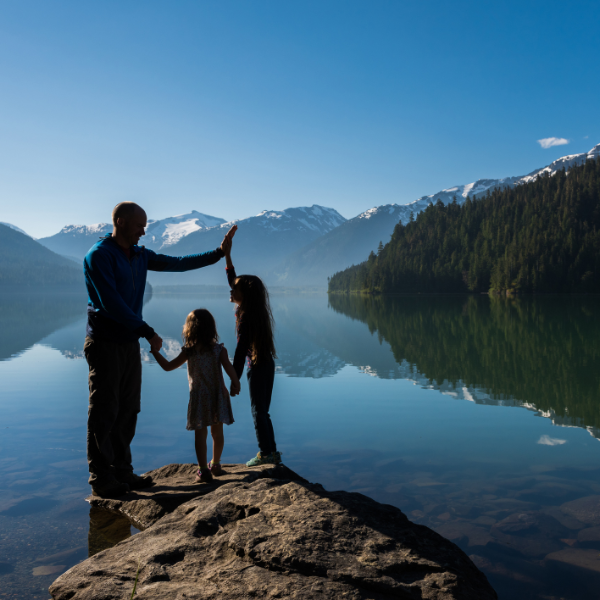 Parent and two children hold hands in front of mountain range
