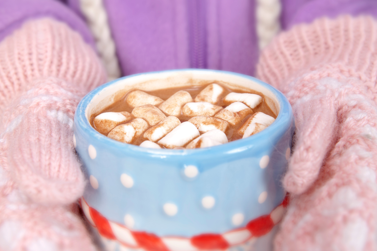 Gloved hands holding hot cocoa