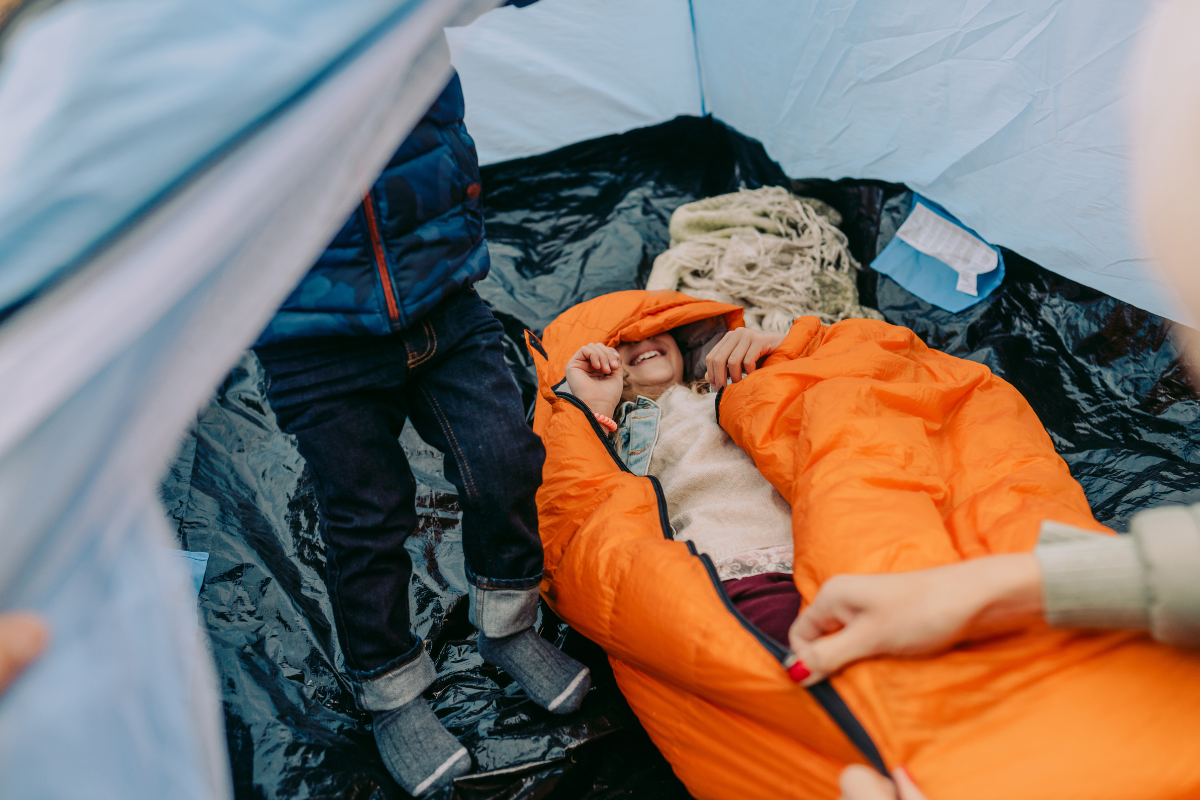 Child smiling inside sleeping bag in tent