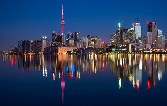 Shown is a colour photograph of a city at night, and its reflection in water.
