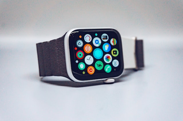 Shown is a colour photograph of a small screen filled with app logos, with a watch band attached.