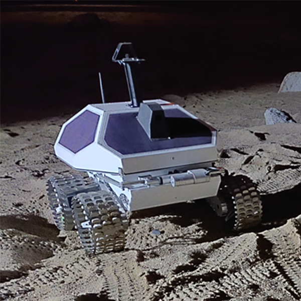 Shown is a colour photograph of the Canadensys lunar rover in its testing environment. It is turned at about 45 degrees.