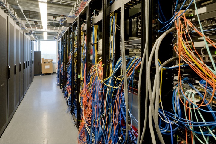 Shown is one aisle in a server room, with the cabling of the servers and other equipment exposed.