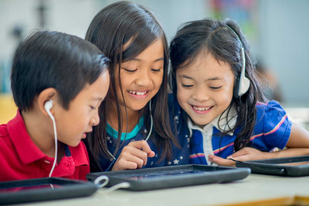 Children looking at tablet with headphones on