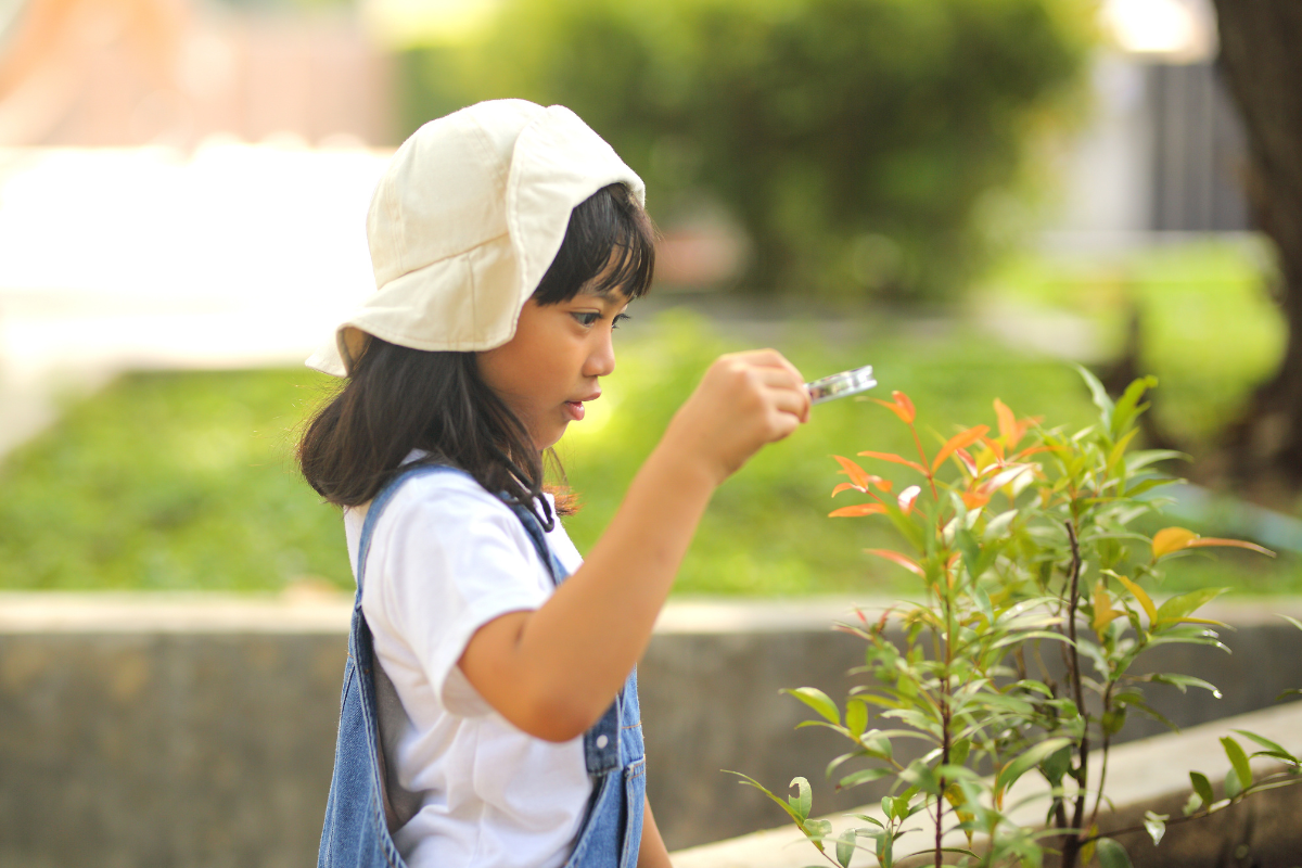 Young child looking at plant through magnifying glass