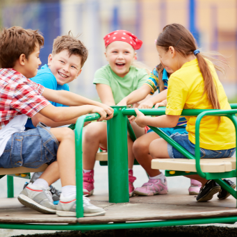 Children having fun on playground roundabout