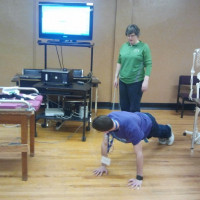 Student in a plank position participates in an activity while a second watches