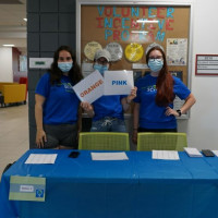three Let's Talk Science Volunteers standing at a blue activity table
