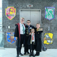 family dressed in wizarding costumes posing in front of house crests