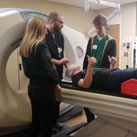 Person in MRI with 3 people standing beside it