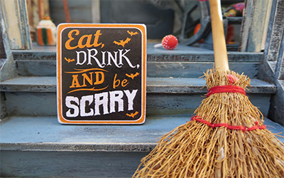 Broom next to a sign that reads "Eat, drink and be scary"