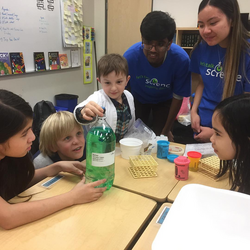 Students working on a science activity with two volunteers
