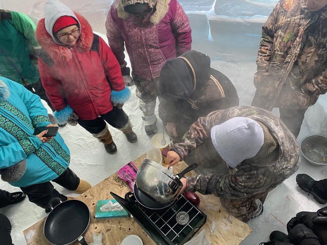 Ian and students in winter clothing cooking on an outdoor stove
