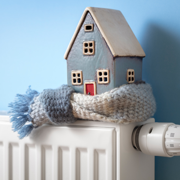 A small blue house wearing a scarf sitting on top of a white radiator.