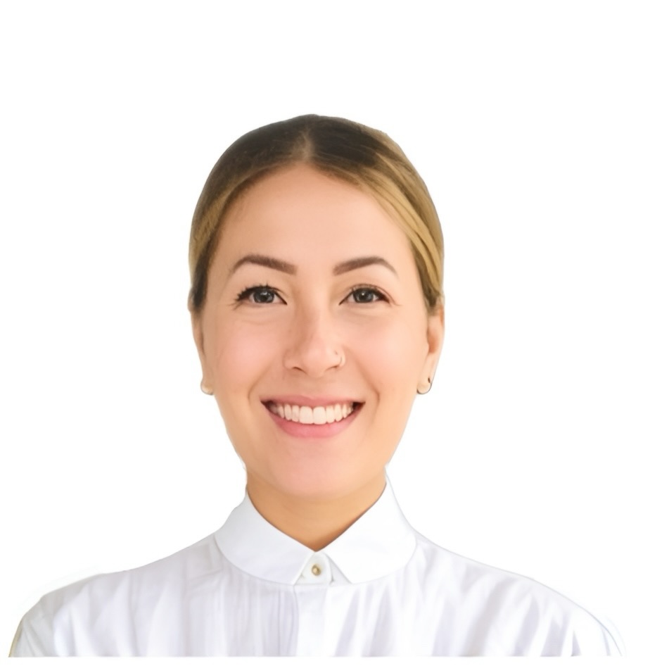 Photo in color, showing the headshot of a woman. She has light colored hair, that is tied back. She is smiling and wearing a white blouse that is buttoned at the neck. The background is white.