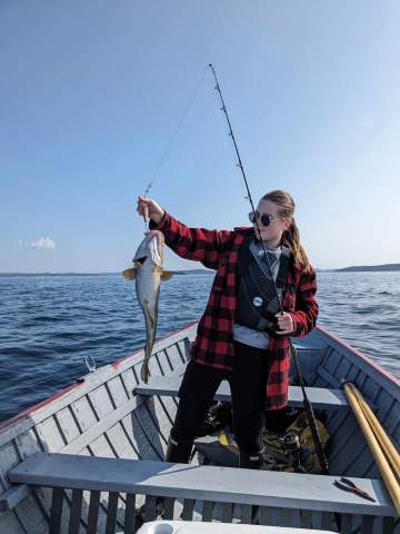 Alena Djukin in an open boat with fish she has caught
