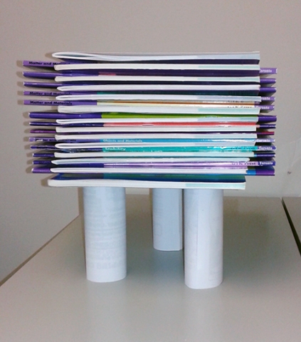 27 books atop three paper cylinders