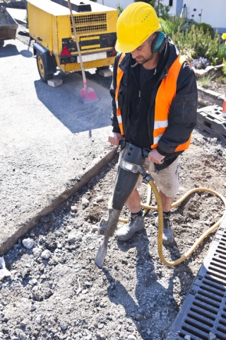 Road worker with jackhammer and compressor