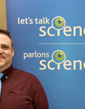 A photo of Greg Ryerson in front of a Let's Talk Science banner