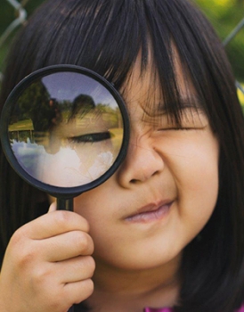 Student looking through magnifying glass
