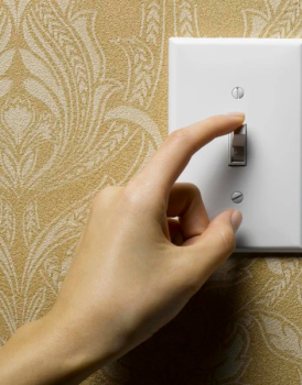 A hand turning off a light switch