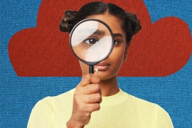 Young woman holding up a magnifying glass against a blue and red background