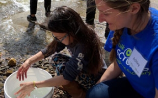 A student works with a Let’s Talk Science Outreach volunteer during a fish release activity