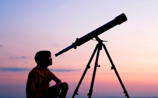 Boy looking through telescope at night
