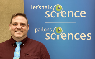 A photo of Greg Ryerson in front of a Let's Talk Science banner