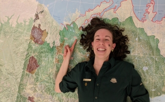 Hayleigh Conway laying on map of NWT and pointing to Inuvik on the map. Taken on GIS Day 2017.