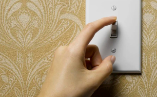 A hand turning off a light switch