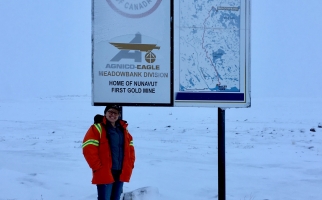 Nancy Duquet-Harvey standing next to Agnico Eagle gold mine sign, at Meadowbank, Nunavut.