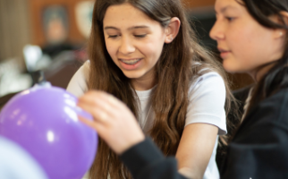 Two girls use a balloon to solve a science task