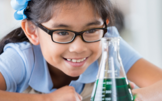 Small girl looking at flask with green solution