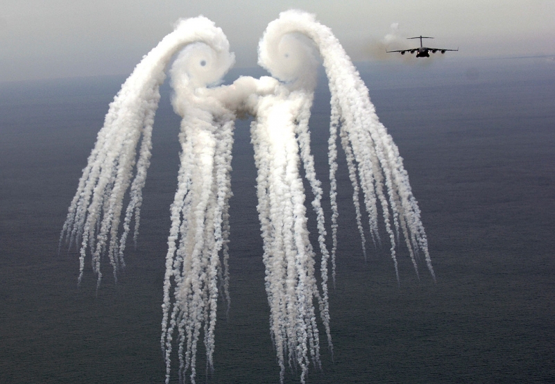 Wake turbulence created by the wingtips of a C-17 Globemaster. The “smoke angel” is caused by flares released by the aircraft 